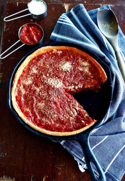 Discover the authentic Chicago-style deep dish pizza, made with a crunchy flaky crust and garnished with thick layers of cheese and tomato sauce.