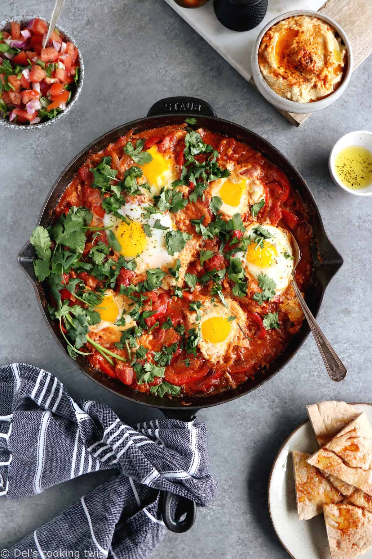 Shakshuka with Feta Cheese is a simple dish consisting of poached eggs in a simmering tomato sauce with feta and spices, traditionally served in a cast iron skillet.