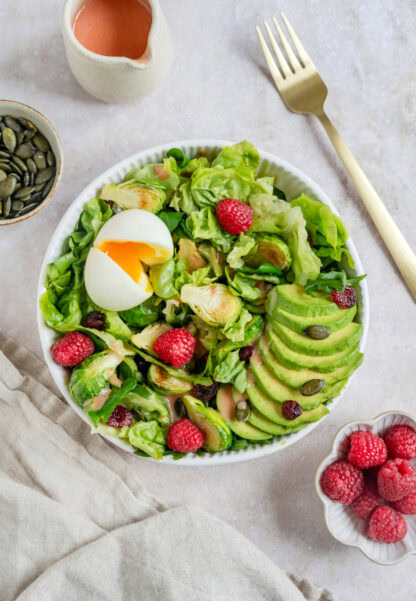 Simple et délicieuse salade d'avocat, framboises et oeufs mollets avec une vinaigrette de framboises.