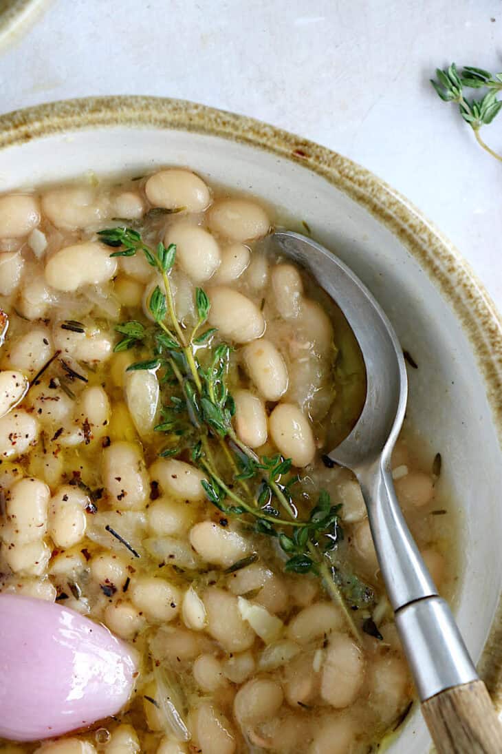 These brothy white beans infused with fresh herbs make a cozy meal packed with flavors. They're easy to make (no soaking time needed).