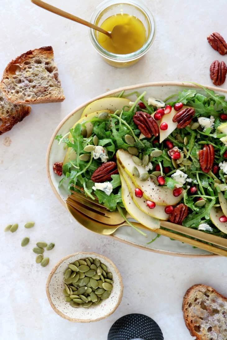 This simple arugula pear salad with blue cheese and pecans is light, fruity, crunchy, and tossed in a simple maple Dijon vinaigrette.