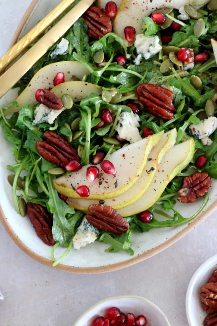 This simple arugula pear salad with blue cheese and pecans is light, fruity, crunchy, and tossed in a simple maple Dijon vinaigrette.