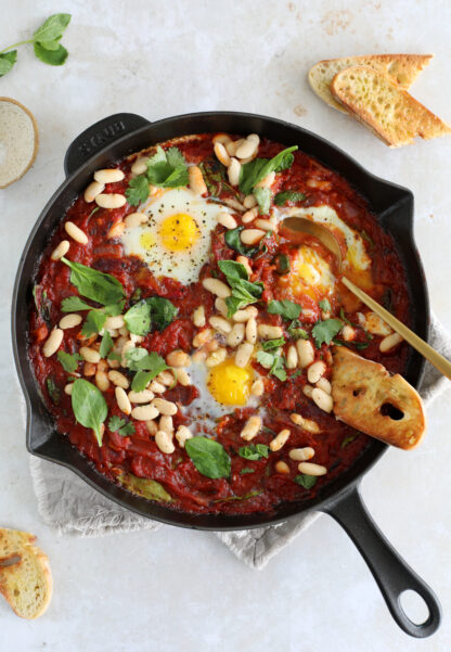 La shakshuka aux haricots blancs et aux pousses d'épinards, c'est un plat d'oeufs pochés à la sauce tomate facile et bon marché.